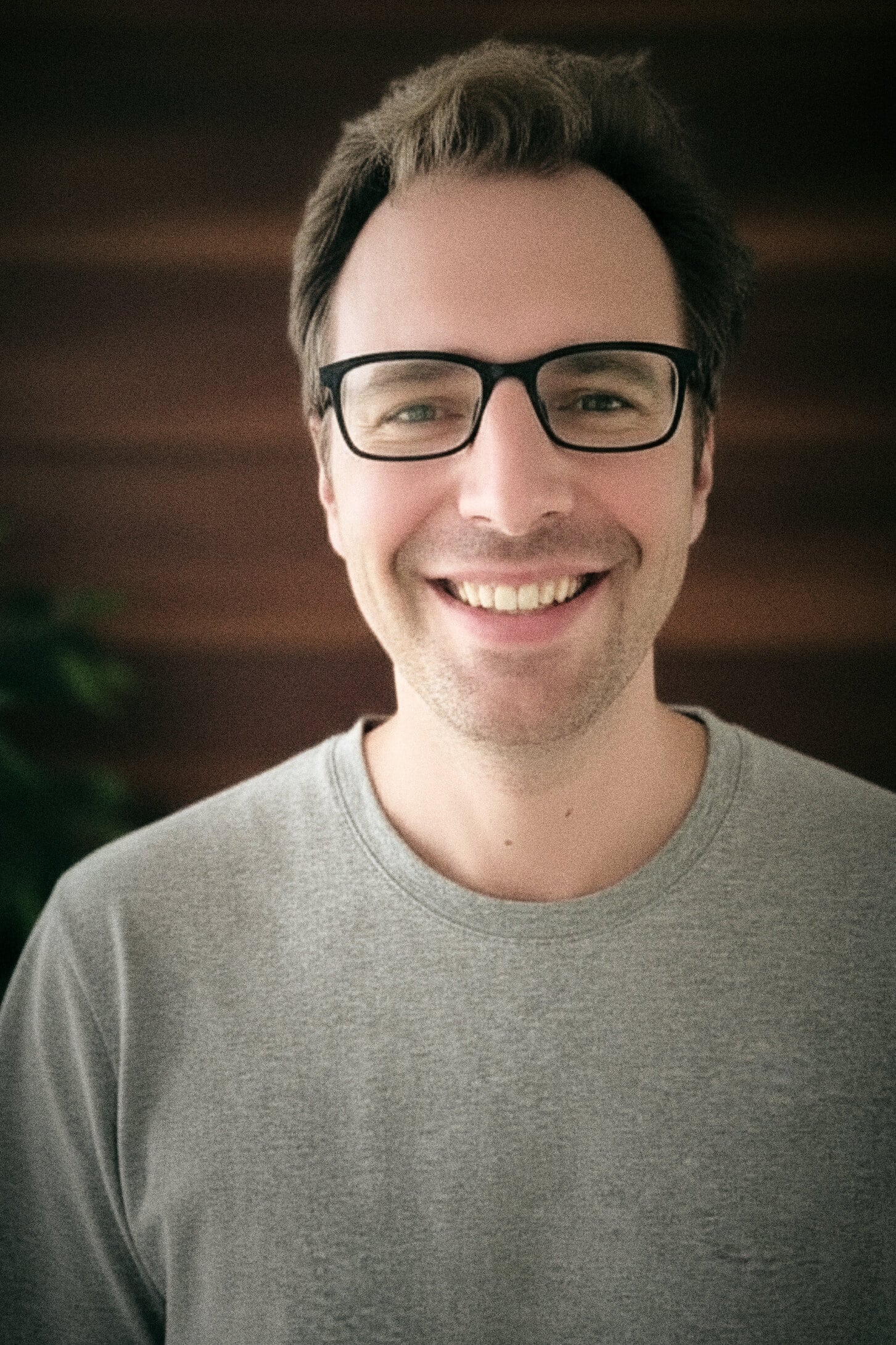 Lächelnder Mann mit Brille und grauem T-Shirt.
